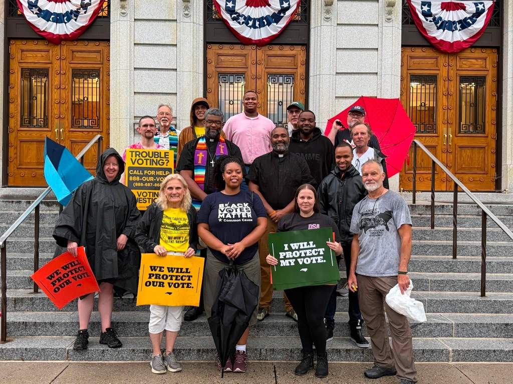 Coalition members on the Guilford County Courthouse steps holding voting rights signs
